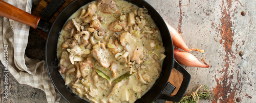 pan with chicken fricassee with mushrooms on the table photo