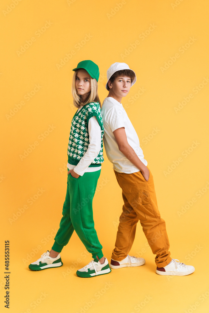 Fototapeta premium White girl and boy looking at camera posing back to back together