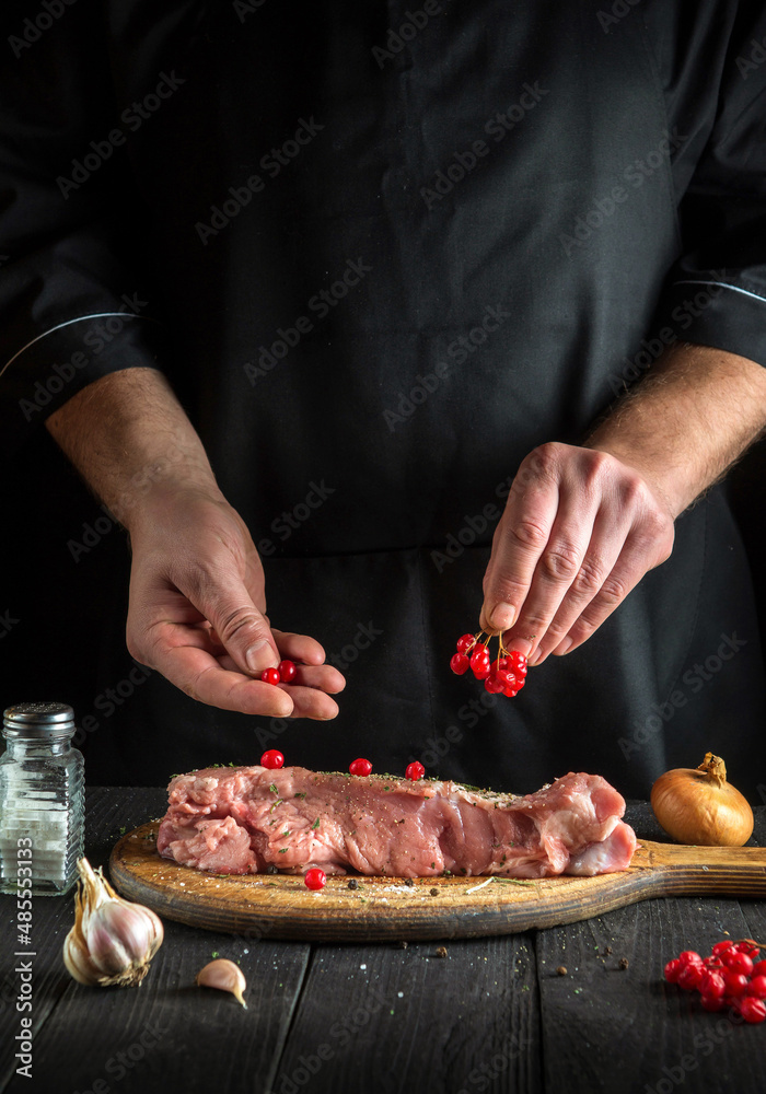 Professional chef prepares raw veal meat. Before baking, the cook puts the viburnum on the beef. National dish is being prepared in the kitchen