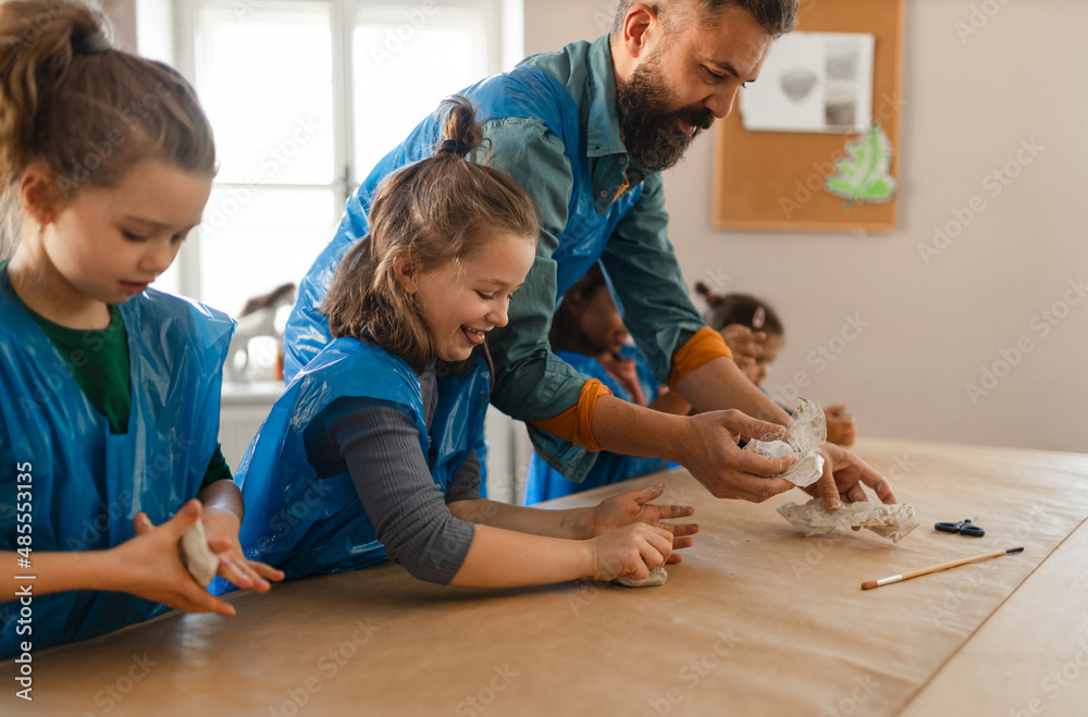 Group of little kids with teacher working with pottery clay during creative art and craft class at school. Group of little kids with teacher working with pottery clay during creative art and craft class at school.