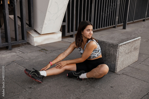 Teenage girl sitting on the floor and resting after training of the city the background
