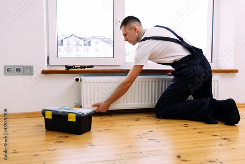 Repair heating radiator close-up. man repairing radiator with wrench