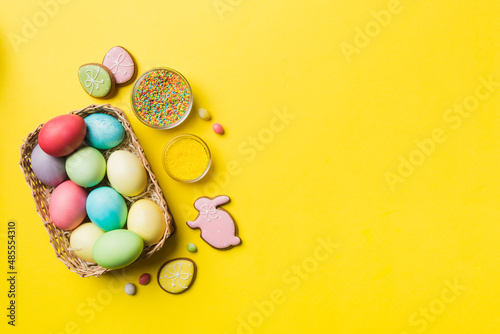 Canvas Print Colorful easter cookies in basket with Multi colors Easter eggs on colored background