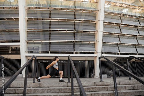 Teenage girl doing sports and stretching exercises outdoor of the city background  © Ankor_stock.