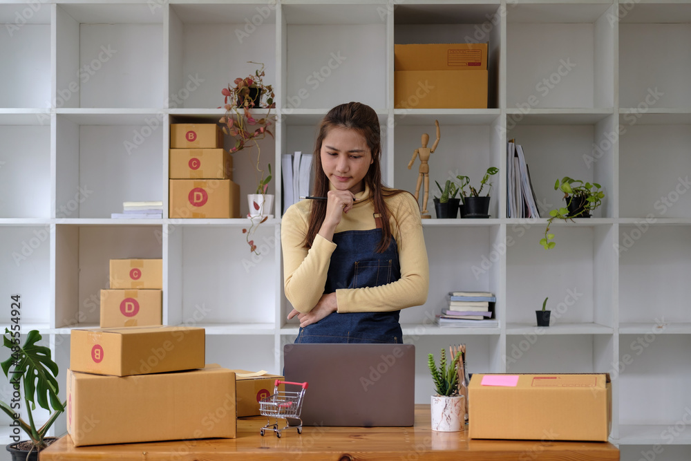 Start up small business entrepreneur SME or freelance asian woman using laptop with box, Young success Asian woman with her hand lift up , online marketing packaging box and delivery, SME concept Start up small business entrepreneur SME or freelance asian woman using laptop with box, Young success Asian woman with her hand lift up , online marketing packaging box and delivery, SME concept