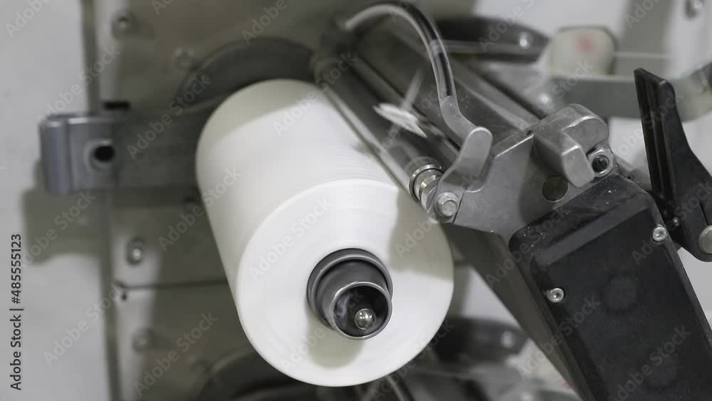 bobbin with the white thread is spinning on the machine close-up. concept of automate manufacturing