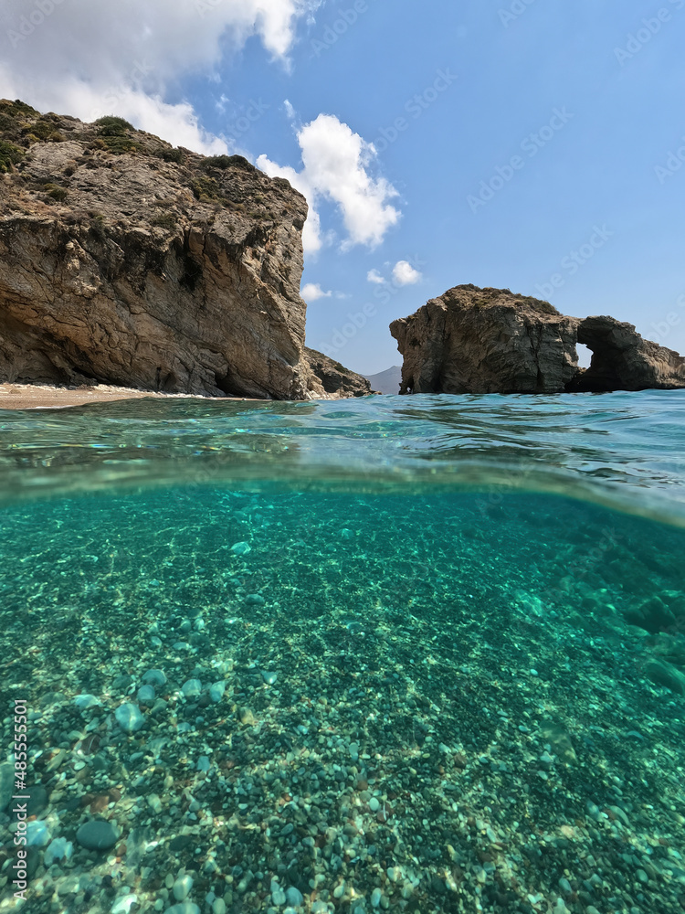 Underwater split photo of natural exotic island rocky bay with turquoise crystal clear sea and small caves