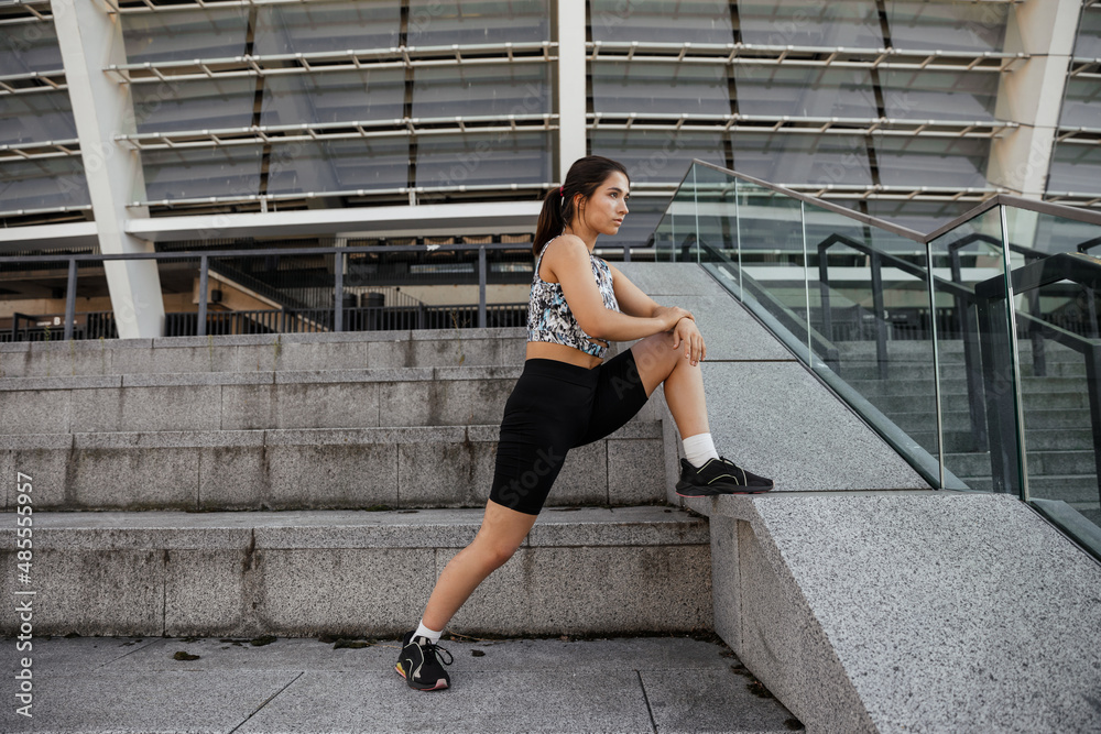 Teenage girl doing sports and stretching exercises outdoor of the city background 