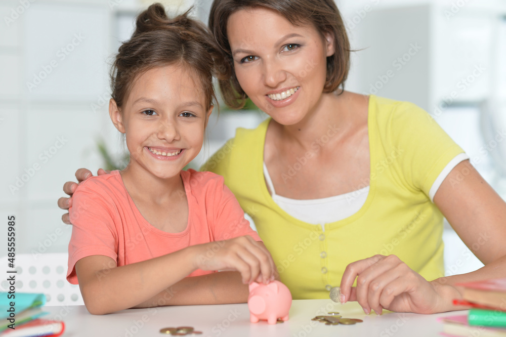 portrait of happy mother with little daughter with piggy bank portrait of happy mother with little daughter with piggy bank