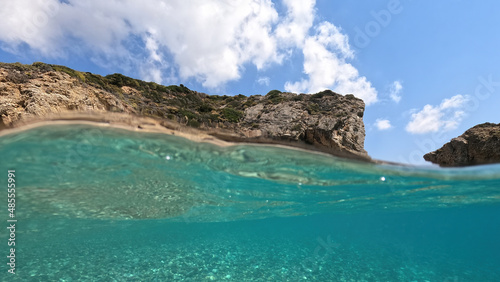 Underwater split photo of natural exotic island rocky bay with turquoise crystal clear sea and small caves