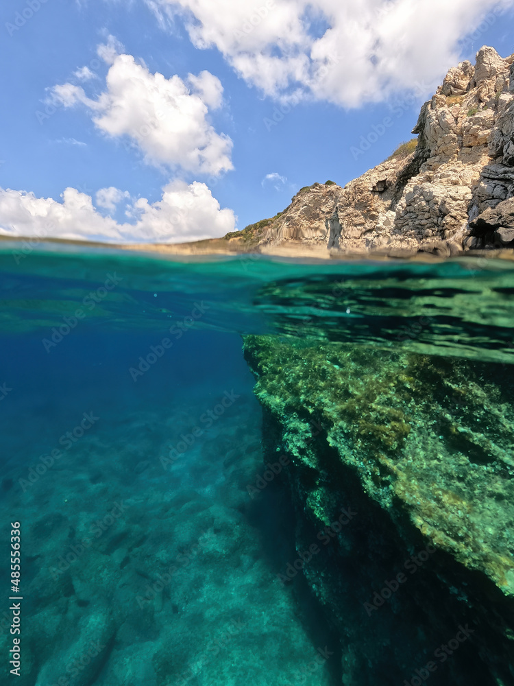 Fototapeta premium Underwater split photo of natural exotic island rocky bay with turquoise crystal clear sea and small caves