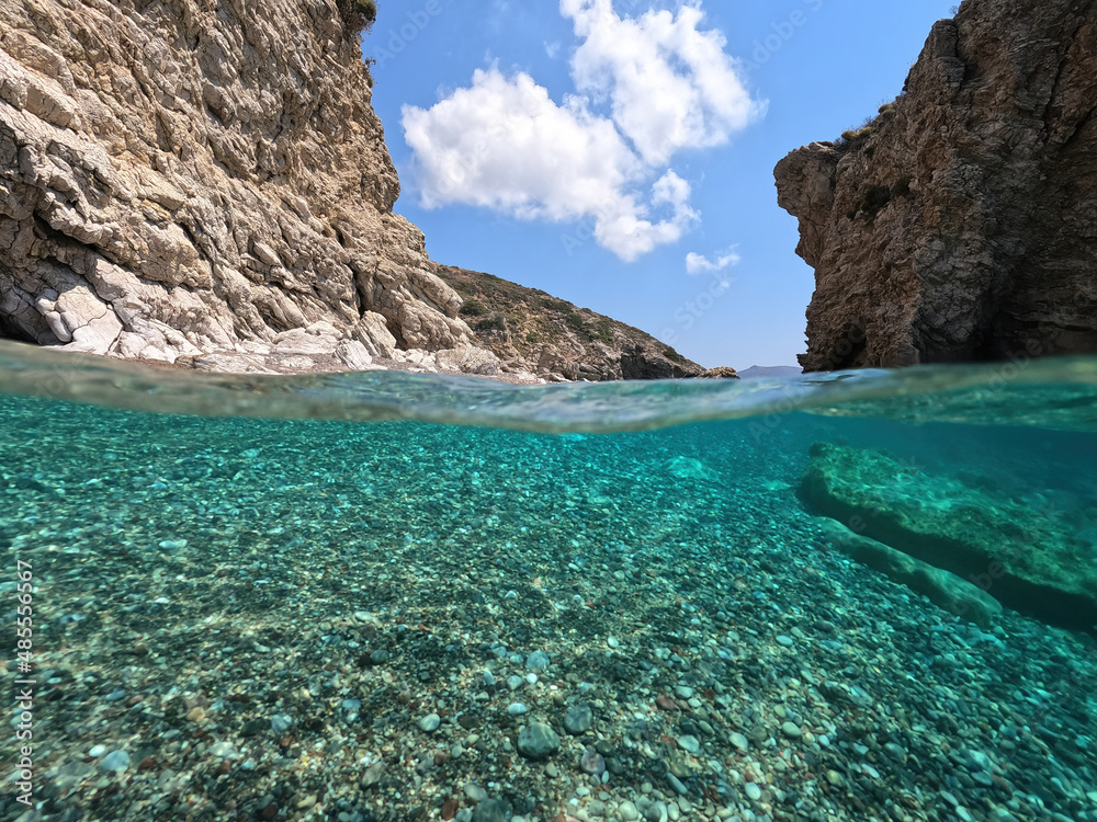 Underwater split photo of beautiful paradise pebble rocky bay of Kaladi with turquoise crystal clear sea and small caves, Kythira island, Ionian, Greece