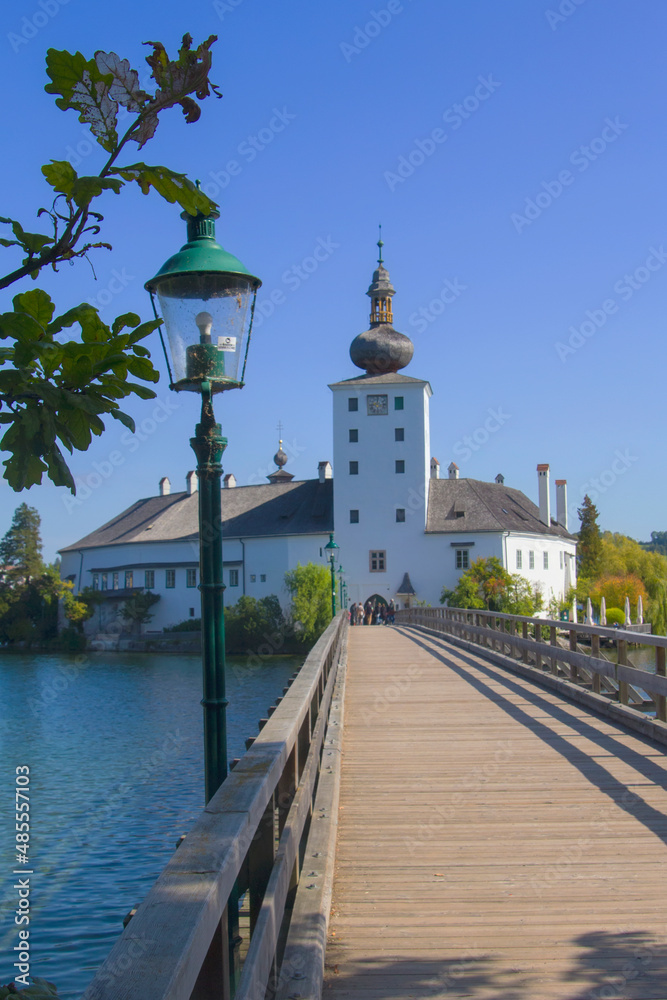 photo background view of the Ort castle on an island in the middle of the Traunsee lake, from the beginning of the wooden bridge, Gmunden, Salzkammergut, Austria, Europe