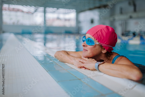 Happy senior woman in swimming pool, leaning on edge. © Halfpoint