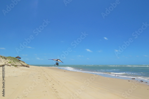 Motorized hang glider taking off on the beach