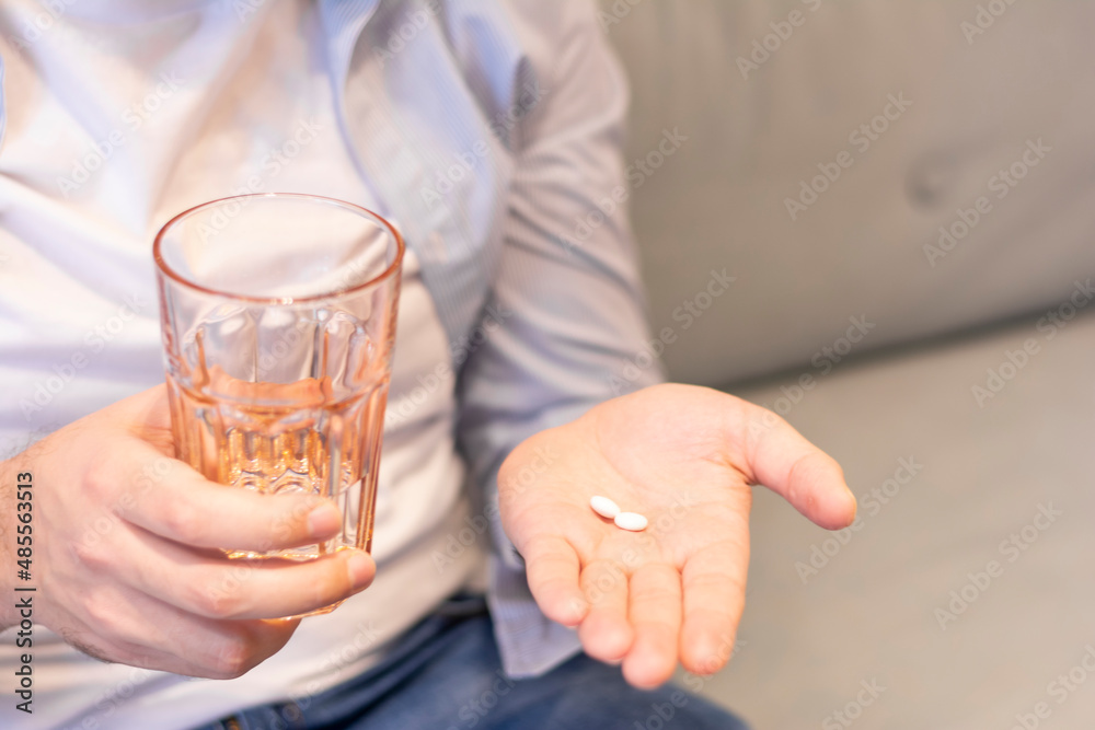 Close-up of a man drinking pills drinking a glass of water holding in his hands treatment concept Close-up of a man drinking pills drinking a glass of water holding in his hands treatment concept