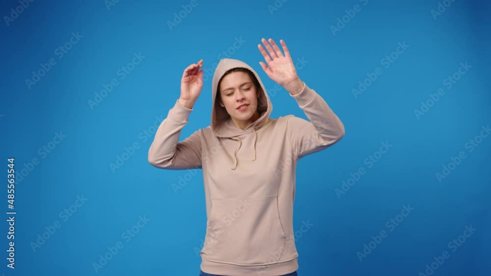 Happy young woman dancing against blue background