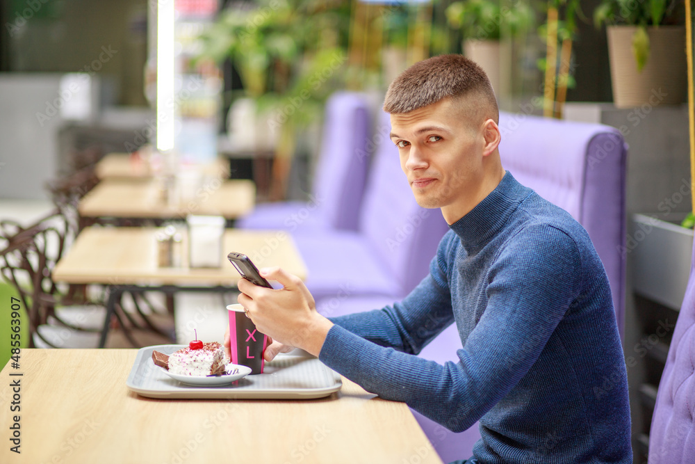 Young man works online. In the hands of a smartphone, gadgets for working on the Internet. A man in a cafe reads the news and works using the phone.
Young man works online. In the hands of a smartphone, gadgets for working on the Internet. A man in a cafe reads the news and works using the phone.