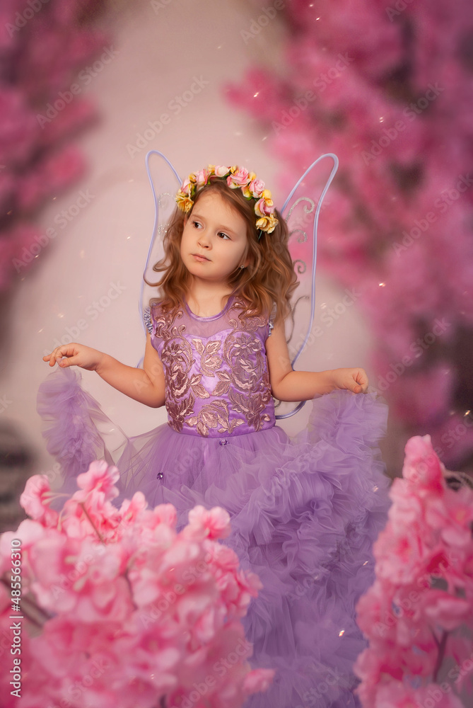 Fototapeta premium charming European girl in a purple dress with a hoop of roses in flowers. Color of the year and March 8 in spring