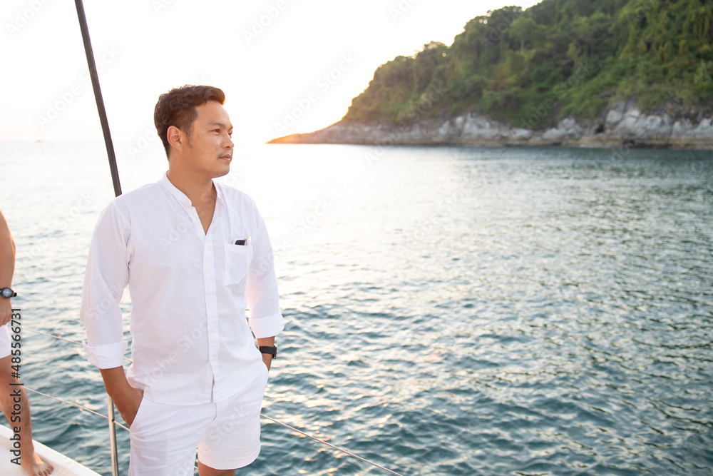 Portrait confident young asian man looking forward and smiling while standing on the yacht Portrait confident young asian man looking forward and smiling while standing on the yacht