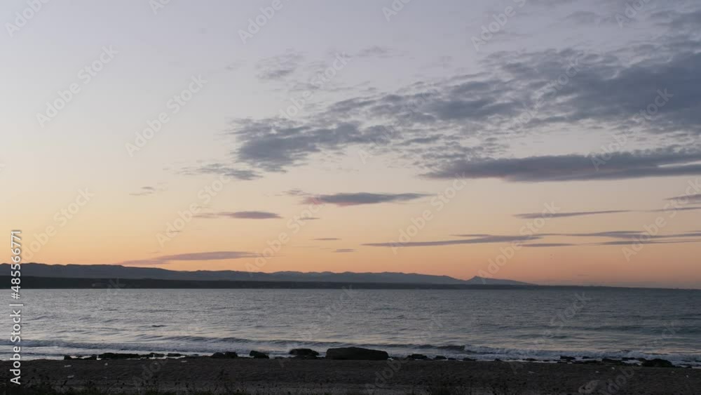 Panoramic view of the coast at sunset. Extreme long shot of coast's panoramic view at sunset with mountains. pink sky and clouds Panoramic view of the coast at sunset. Extreme long shot of coast's panoramic view at sunset with mountains. pink sky and clouds