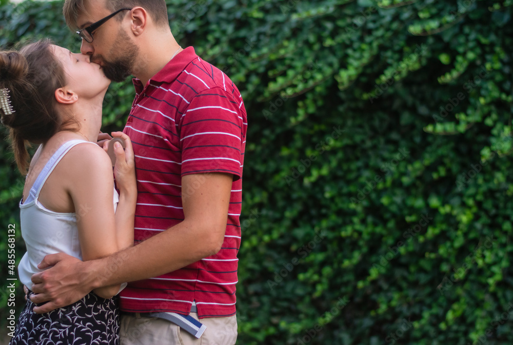 Young couple kissing in casual outfits on a date outdoors in summer on a sunny day Young couple kissing in casual outfits on a date outdoors in summer on a sunny day