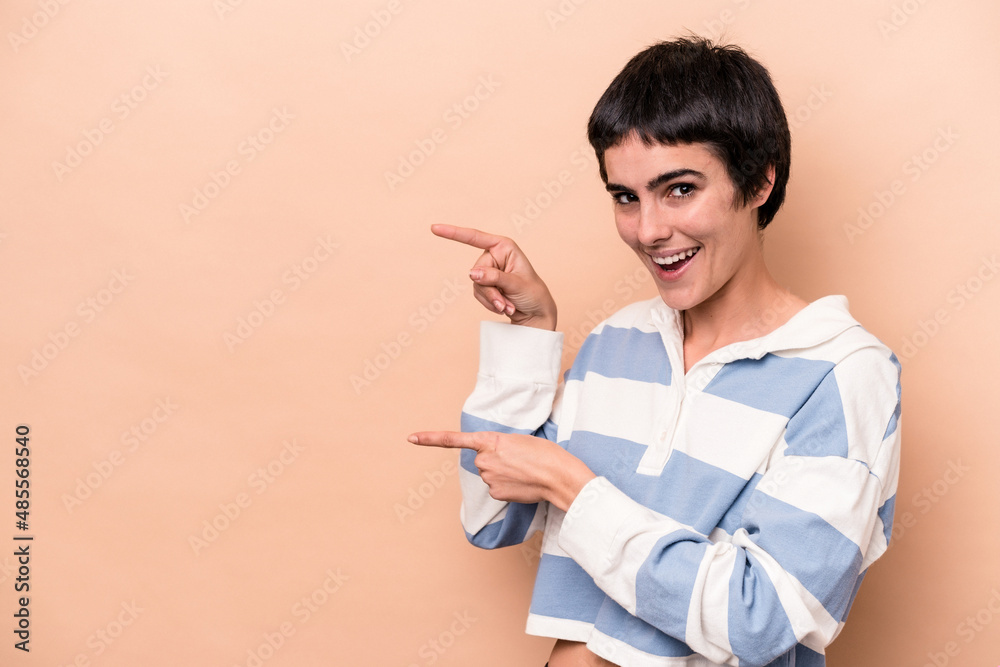 Young caucasian woman isolated on beige background excited pointing with forefingers away. Young caucasian woman isolated on beige background excited pointing with forefingers away.
