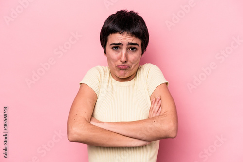 Young caucasian woman isolated on pink background shrugs shoulders and open eyes confused.