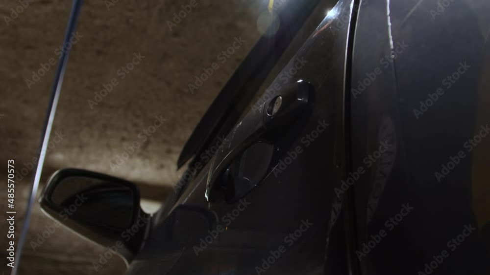 Zoom in shot of female hand opening and closing car's door at parking lot. Close up of woman's hand with manicure opening dark blue car's door at underground parking Zoom in shot of female hand opening and closing car's door at parking lot. Close up of woman's hand with manicure opening dark blue car's door at underground parking