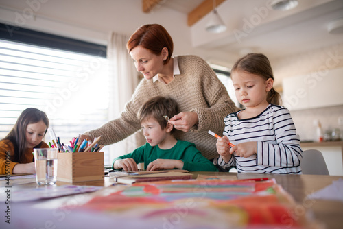 Mother of three little children supervising them when diong homework at home.