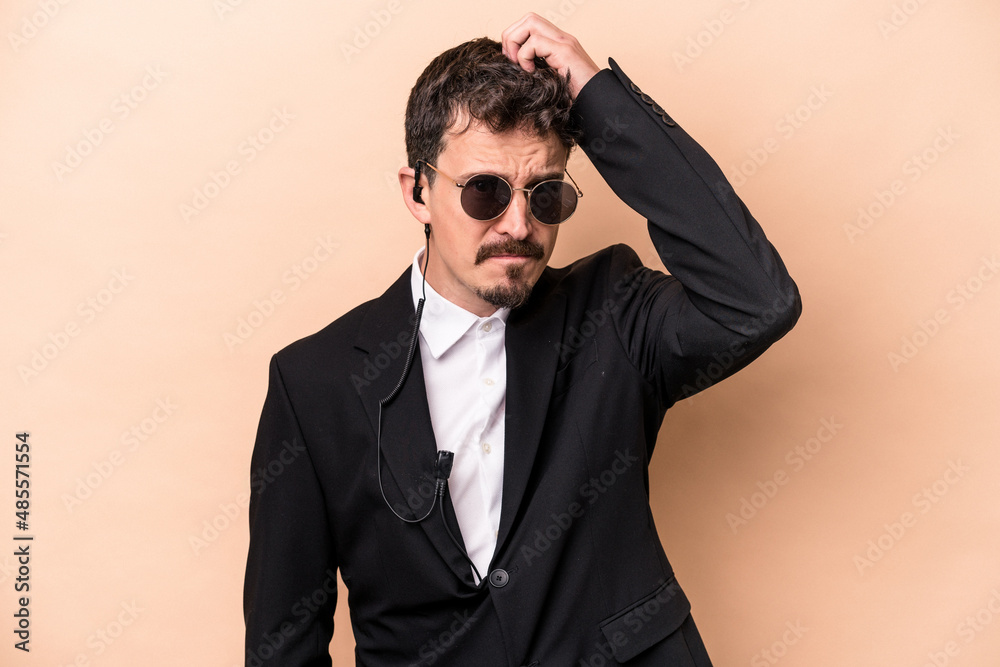 Young bodyguard caucasian man isolated on beige background being shocked, she has remembered important meeting. Young bodyguard caucasian man isolated on beige background being shocked, she has remembered important meeting.