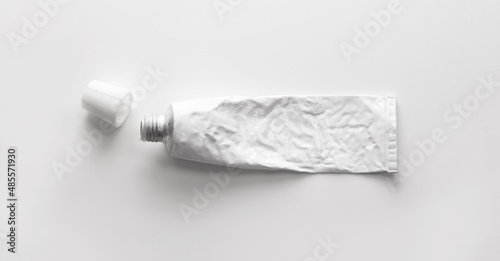 A blank white tube commonly used for pharmaceutical use or chemical products such as ointment, adhesives.
real life used condition. Metal tube. open lid or cap. Isolated on natural white background.