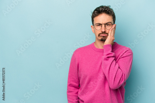 Young caucasian man isolated on blue background who feels sad and pensive, looking at copy space.