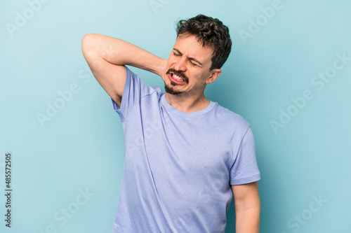 Young caucasian man isolated on blue background tired and very sleepy keeping hand on head.