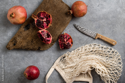 Wallpaper Mural Beautiful red pomegranate fruit composition on a concrete background. Half pomegranate and ripe pomegranate fruit with rustic wooden board, knife and string bag. Top view. Torontodigital.ca