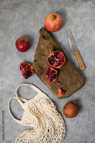 Wallpaper Mural Beautiful red pomegranate fruit composition on a concrete background. Half pomegranate and ripe pomegranate fruit with rustic wooden board, knife and string bag. Top view. Torontodigital.ca