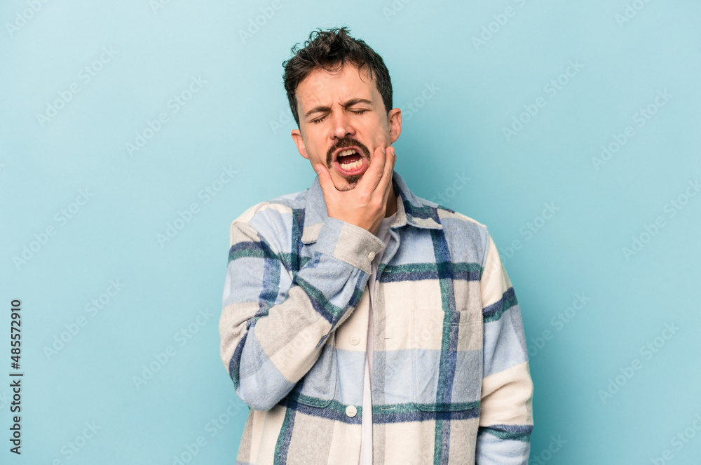 Young caucasian man isolated on blue background having a strong teeth pain, molar ache. Young caucasian man isolated on blue background having a strong teeth pain, molar ache.