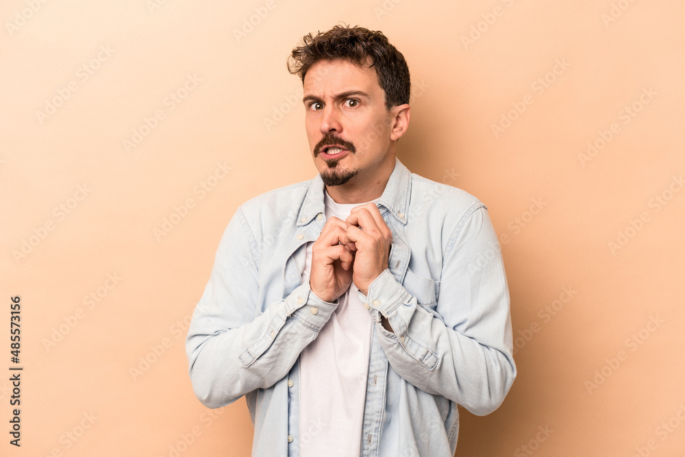Young caucasian man isolated on beige background scared and afraid. Young caucasian man isolated on beige background scared and afraid.