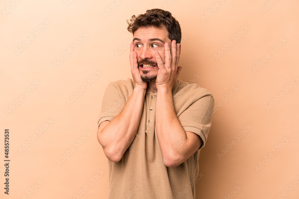 Young caucasian man isolated on beige background scared and afraid.