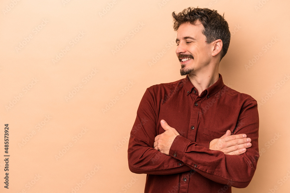 Young caucasian man isolated on beige background smiling confident with crossed arms. Young caucasian man isolated on beige background smiling confident with crossed arms.