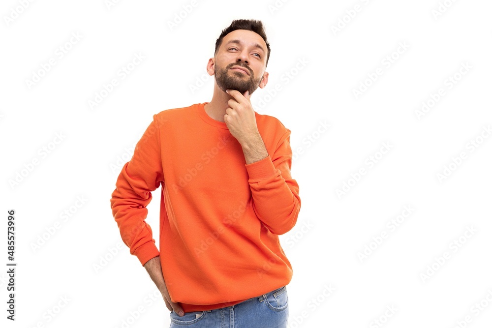 a pensive man in an orange sweater holds his hand at his chin looking thoughtfully up and forward a pensive man in an orange sweater holds his hand at his chin looking thoughtfully up and forward