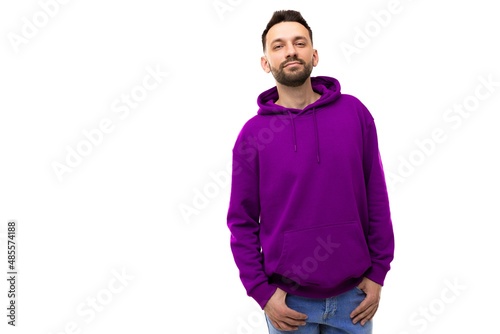 strong young man with beard in purple hoodie on white background with copyspace