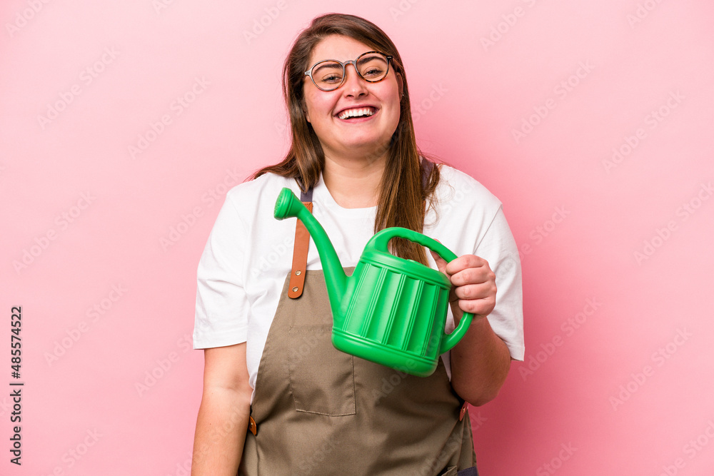 Young gardener caucasian overweight woman holding watering can isolated background laughing and having fun. Young gardener caucasian overweight woman holding watering can isolated background laughing and having fun.