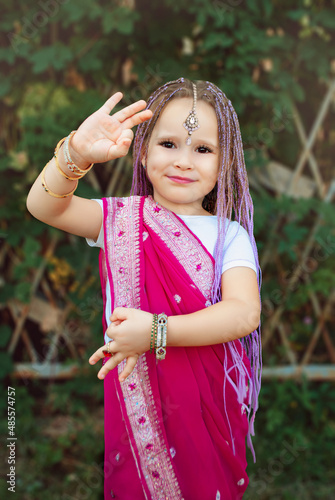 Indian girl in pink sarri in cherry blossoms against a backdrop of green grass with purple braids on March 8 in spring photo