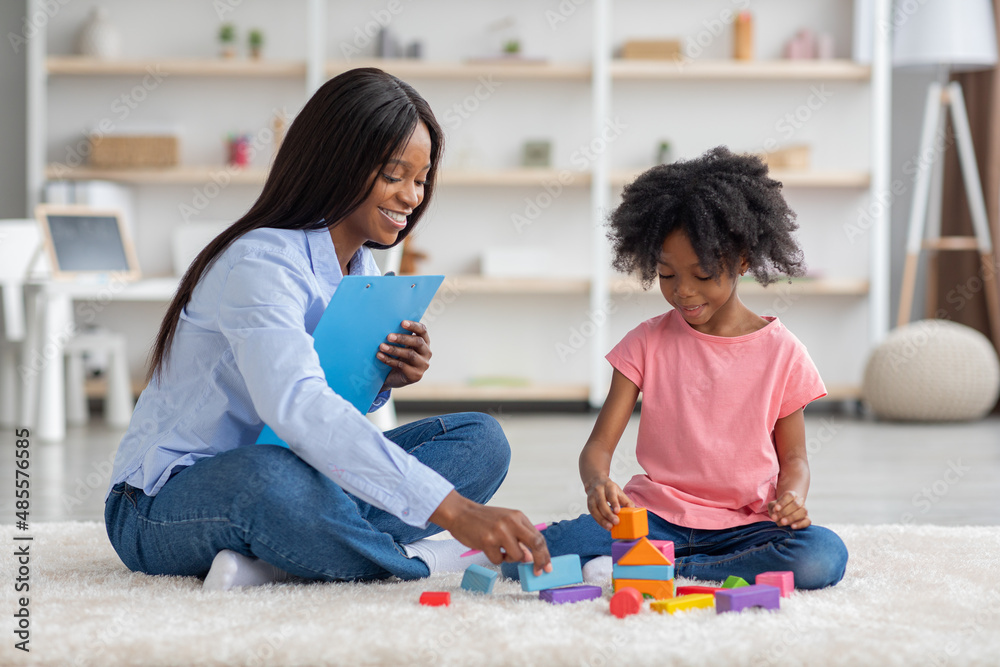 Happy black girl and child development specialist playing with bricks Happy black girl and child development specialist playing with bricks