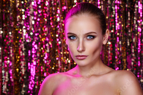 Beauty portrait of a High Fashion woman in colorful bright neon lights posing On colourful vivid sequin background