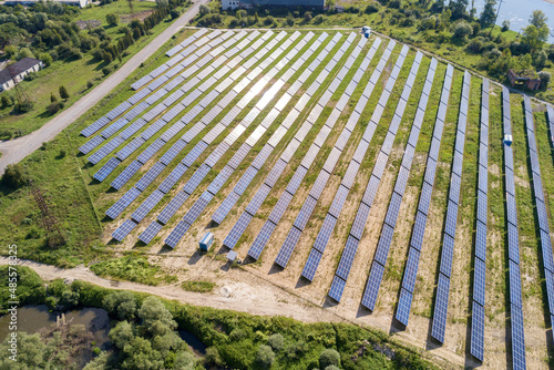 Fototapeta Naklejka Na Ścianę i Meble -  Aerial view of solar power plant on green field. Electric farm with panels for producing clean ecologic energy