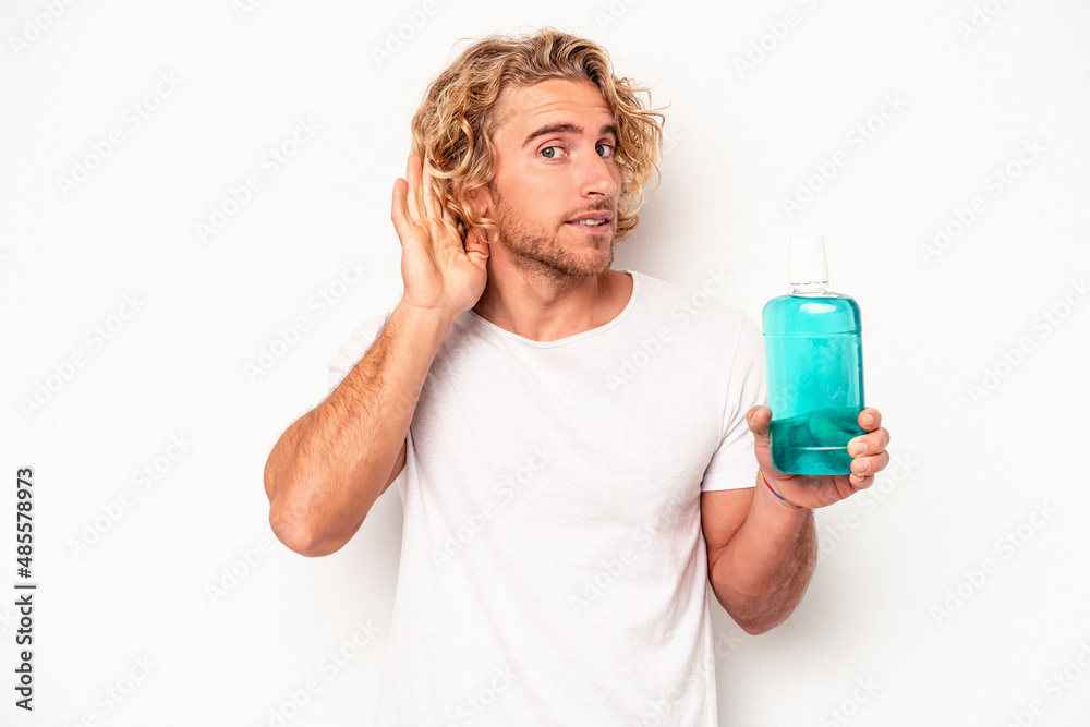 Young caucasian man holding a clapperboard isolated on white background trying to listening a gossip. Young caucasian man holding a clapperboard isolated on white background trying to listening a gossip.