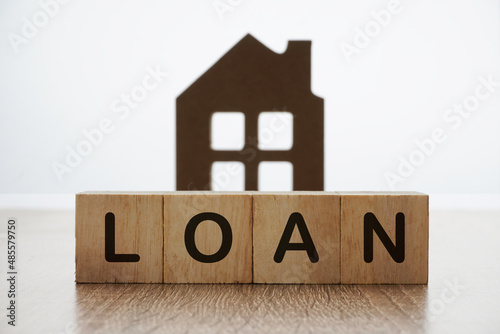 Loan wording on a wooden cube over home replica. financial concept