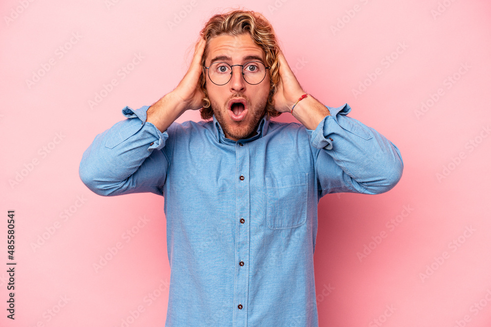 Young caucasian man isolated on pink background being shocked, she has remembered important meeting.
